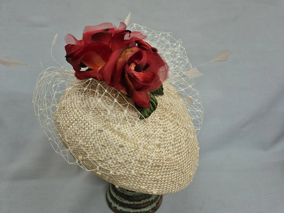 Cream straw hat with netting and red flowers.