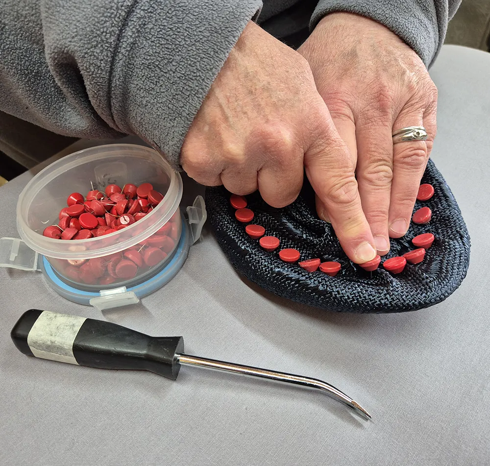 Susan creating a black straw hat.