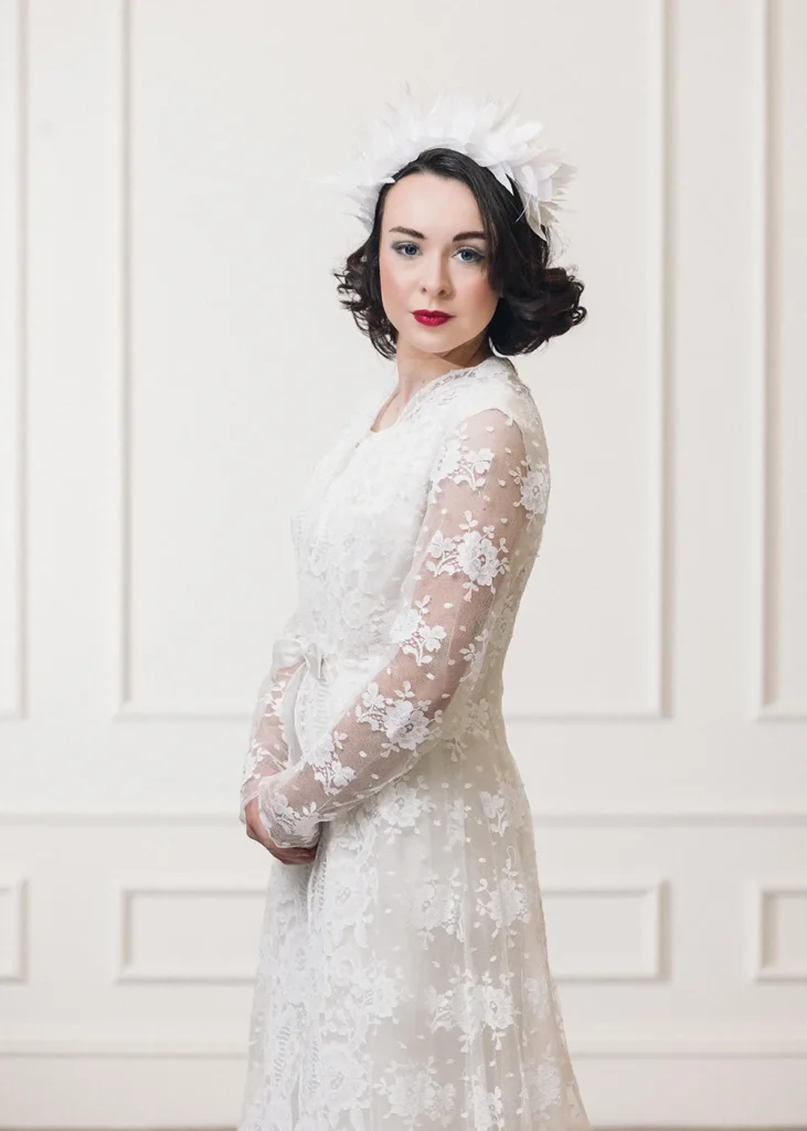 Bride wearing a white lace wedding dress and a feather crown.