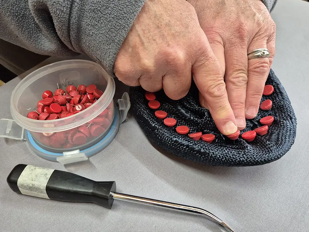 Susan pinning out a black hat brim.